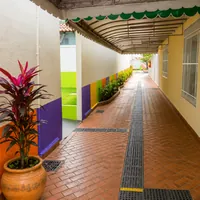 Corredor coberto com piso cerâmico e vaso de planta da Escola Manoel de Barros na Vila Almeida Lima em Campo Gra
